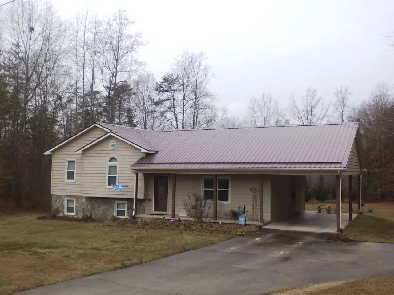 Burgundy metal roof on a tan split level home with an attached carport in Prospect Heights
