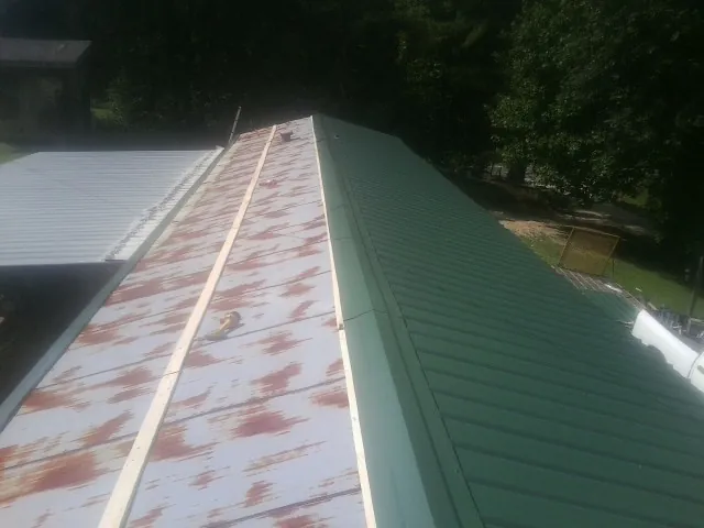 Old rusted panels beside newly installed green metal roofing — Wind Damage Roof Repair by Roofing Brothers in Prospect Heights
