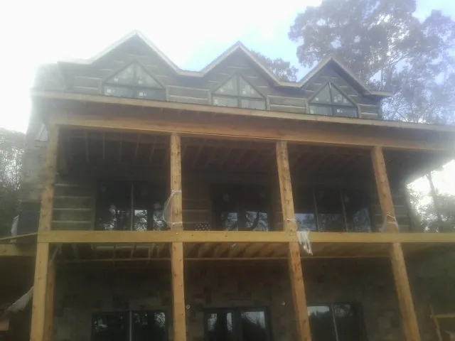 Dormers and porch framing on a large log home under construction — Roof Coating work by our crew in Prospect Heights