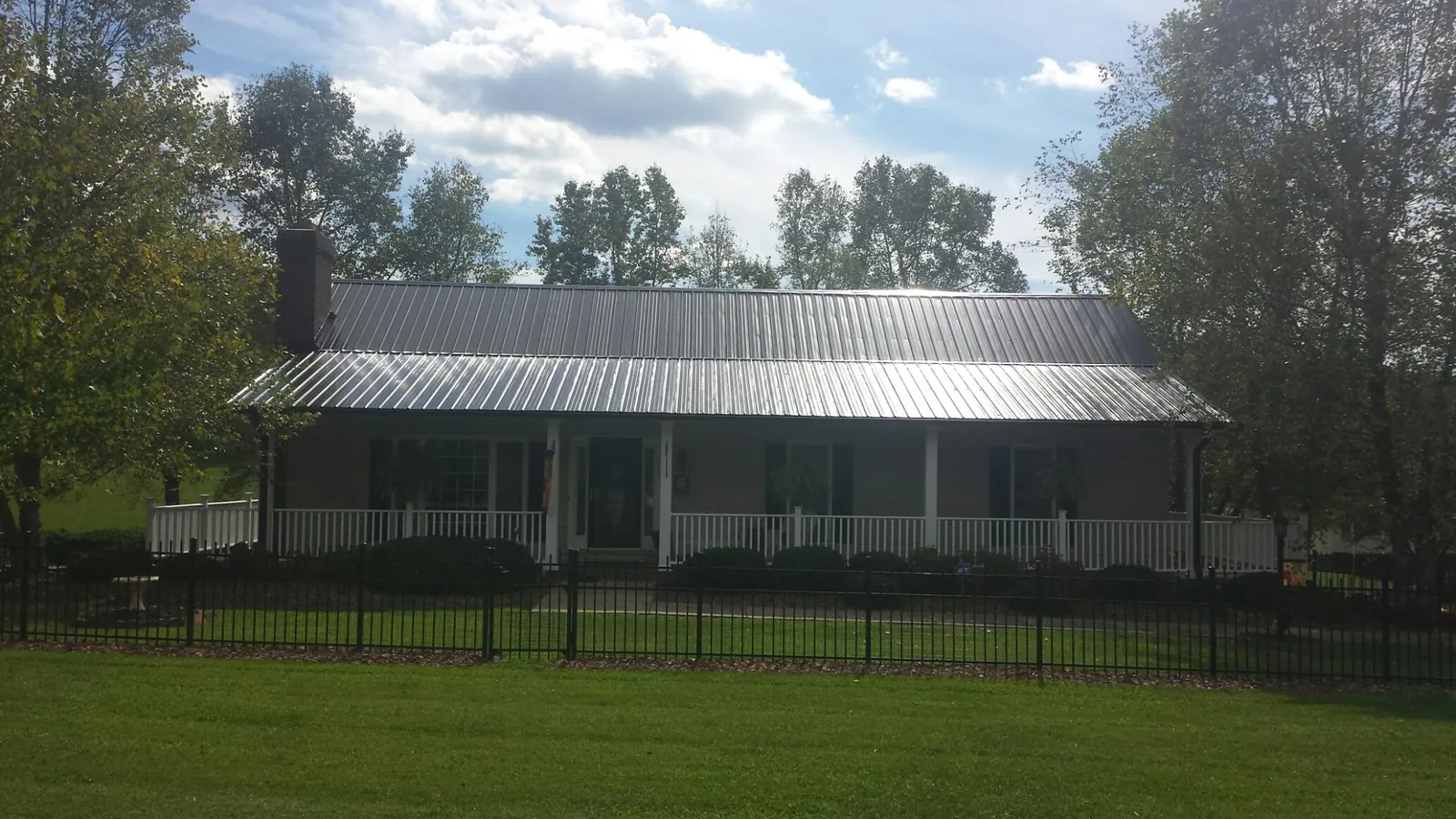 Gray metal roof on a brick ranch with a full width front porch — Gutter Guard Installation work by our crew in Prospect Heights