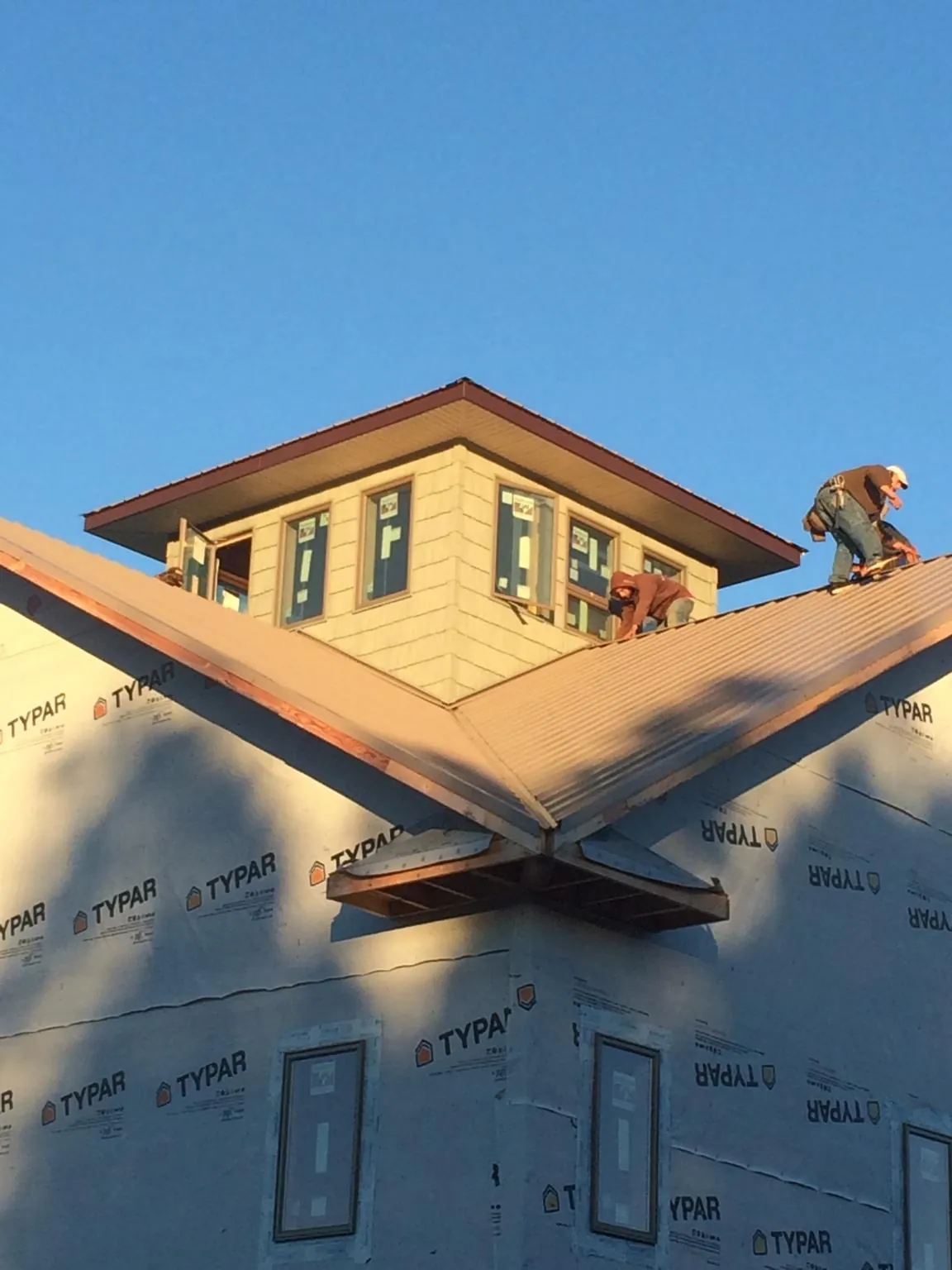 Roofers working around a rooftop cupola on a new metal roof at sunset — Roof Waterproofing in Prospect Heights by Roofing Brothers